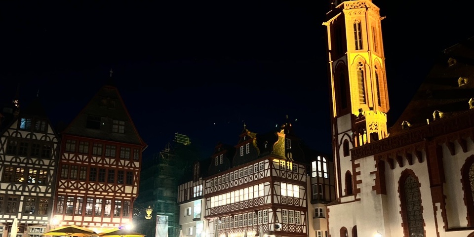 Illuminated half-timbered buildings and church at Frankfurt's Römerberg at night